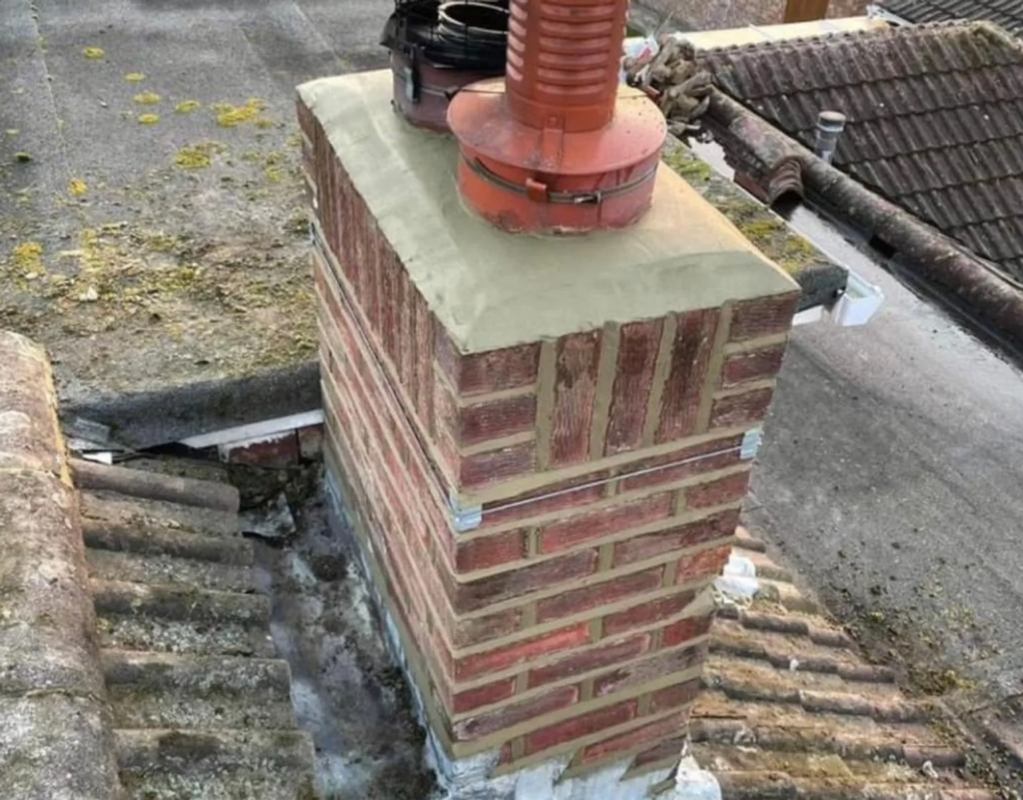 Repaired brick chimney on a tiled roof