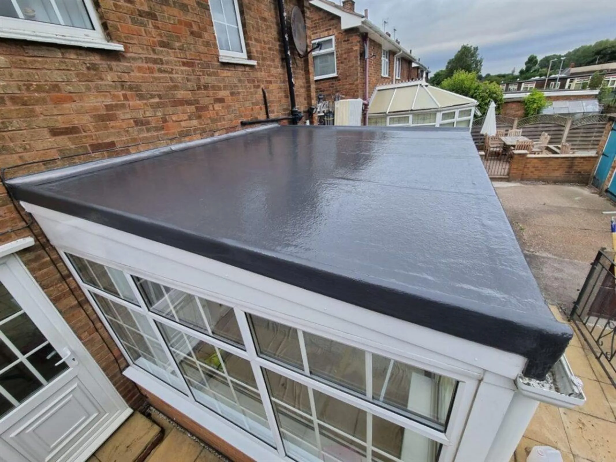 Newly finished flat roof on a conservatory attached to a brick house