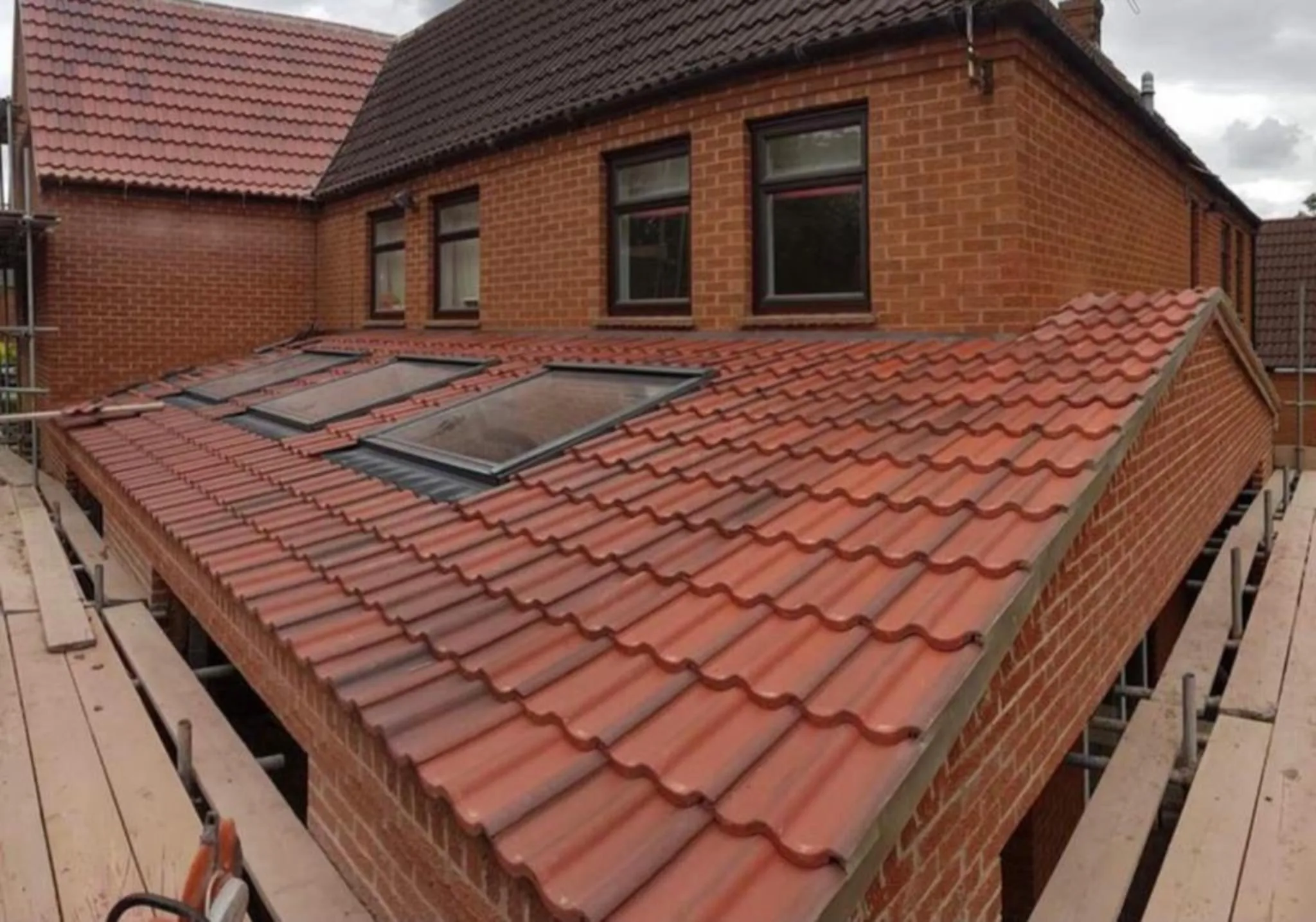 Newly installed tiled roof on a brick house with scaffolding in Oxfordshire