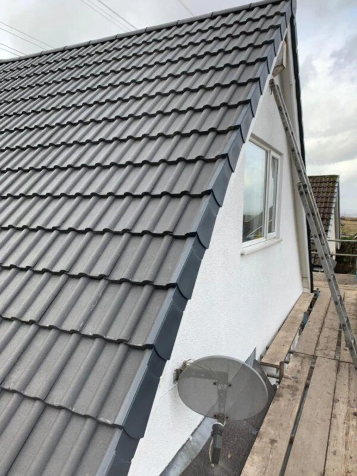 Roofer carrying out repairs on a tiled roof with scaffolding